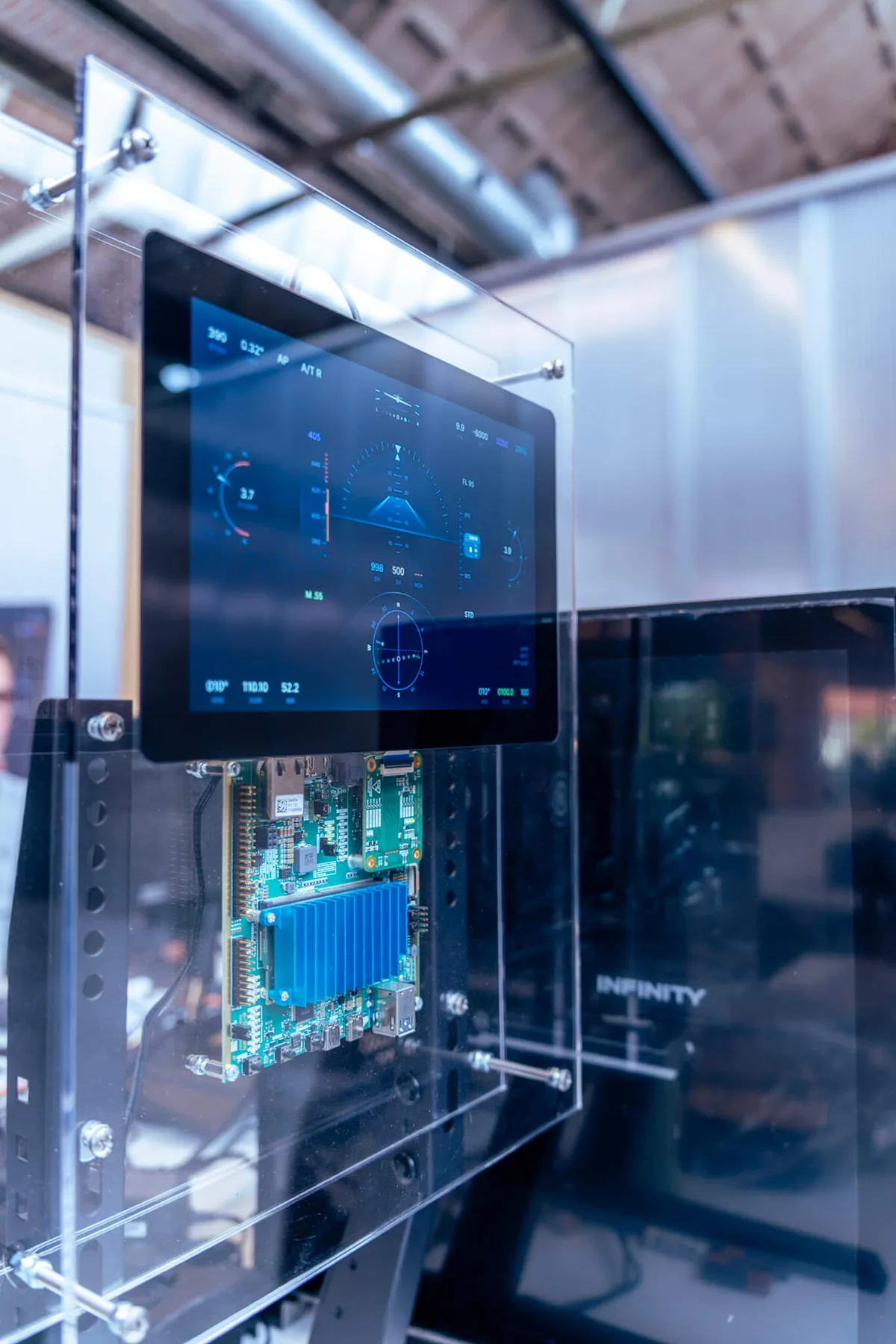 Touchscreen with a cockpit interface in a clear acrylic stand, with the electronics board visible below it